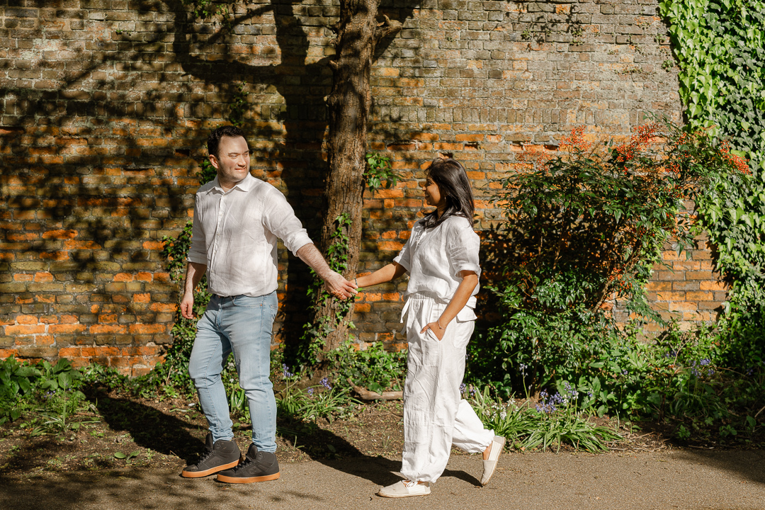 Engaged couple walking in the park at St Albans cathedral